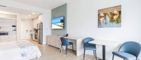 Une chambre d’hôtel moderne équipée d’un lit, d’un bureau, de deux chaises, d’une télévision et d’un tableau.