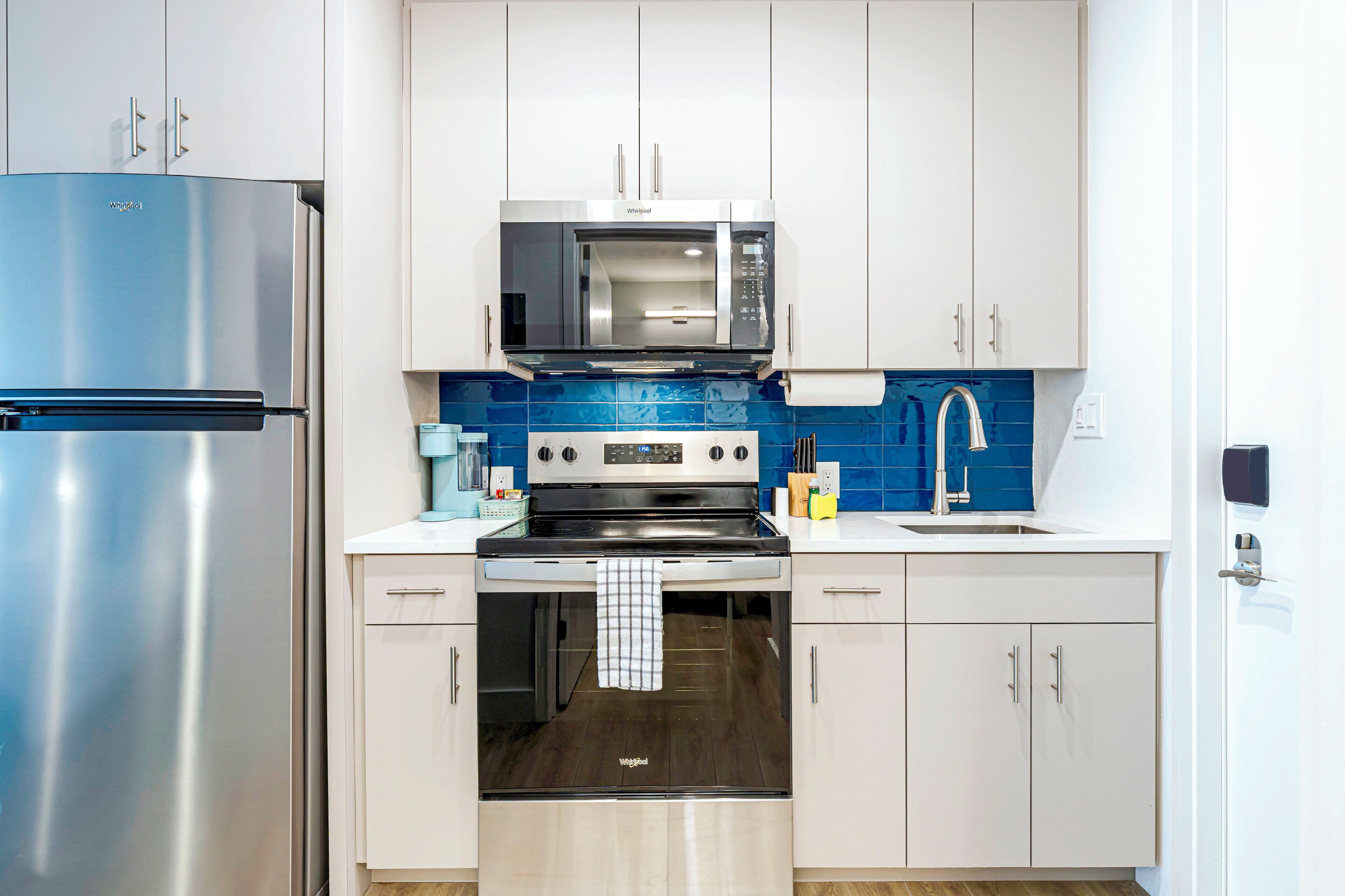 A modern kitchen with a stainless steel refrigerator, a microwave, a stove, and a sink.