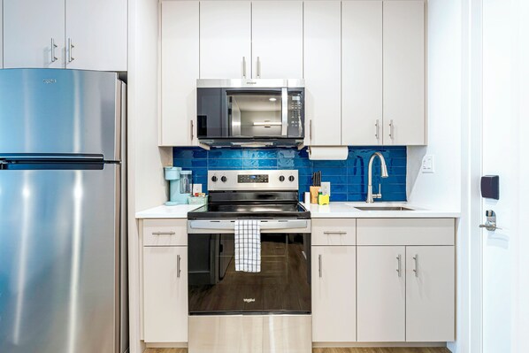 Una cocina moderna con un refrigerador de acero inoxidable, un microondas, una estufa y un lavaplatos.