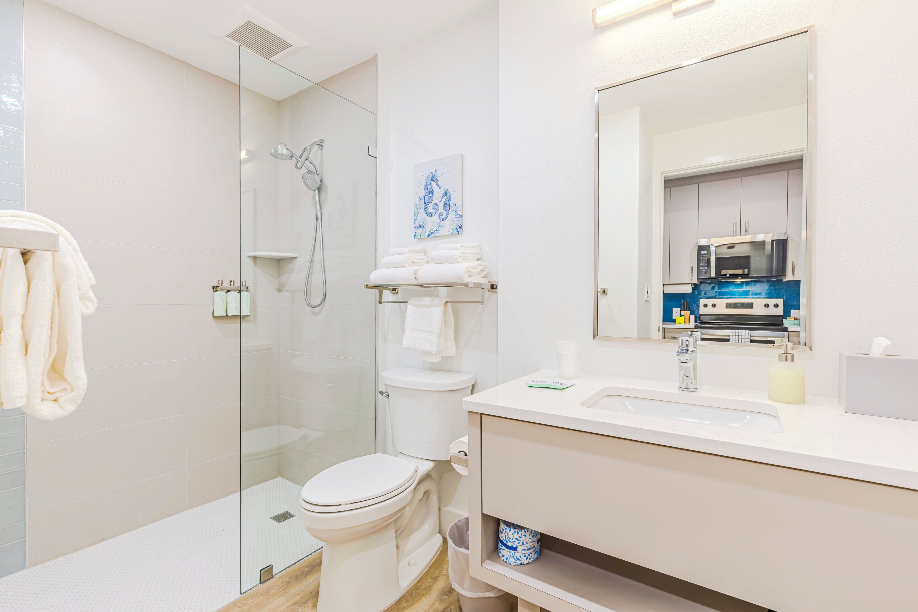 A modern bathroom with a glass-enclosed shower, a toilet, and a sink with a mirror above.