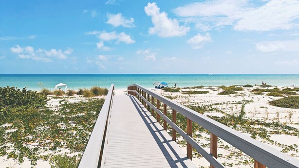 A wooden boardwalk leading to a beach with clear skies and calm waters. - Shalimar Beach Resort (Sanibel)