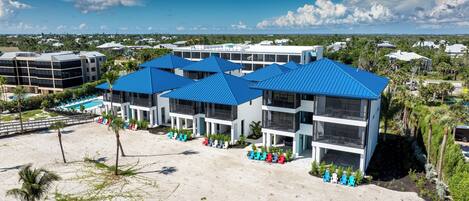 A beachfront hotel with multiple blue-roofed buildings, a pool area, and a sandy beach.