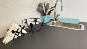 A kitchen with a sink, a utensil holder, and a dish rack.