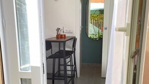 An open door leading to a room with a table and chairs, a small window, and a view of the outside.