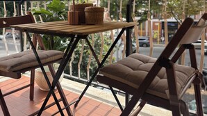 Un balcon avec un auvent à rayures, une table avec des chaises, une plante en pot et des paniers en osier.