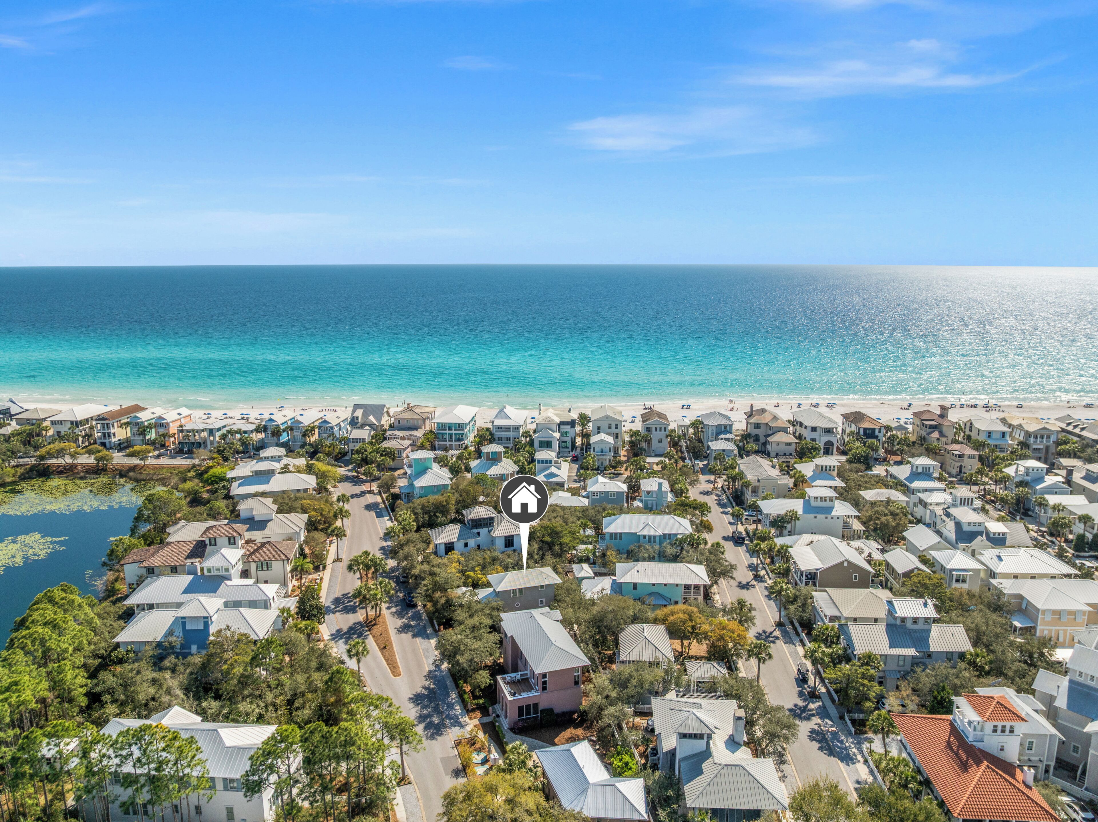 A coastal residential area with houses, a beach, and a clear sky.