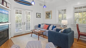 A living room with a sofa, coffee table, striped ottoman, and a television. - Seabatical! 3BR 2BA Coastal Retreat for 8 Relax, Unwind, and Recharge (Panama City Beach)