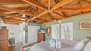 A bedroom with a wooden ceiling, a bed with white bedding, a dresser, and a painting on the wall. - Seabatical! 3BR 2BA Coastal Retreat for 8 Relax, Unwind, and Recharge (Panama City Beach)