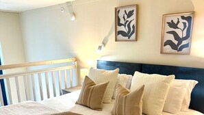Una cama bien hecha con un cabecero azul, ropa de cama blanca y varios cojines decorativos.