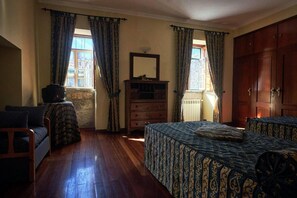 Ein Schlafzimmer mit Bett, Kommode, Spiegel und einem Fenster mit Vorhängen.