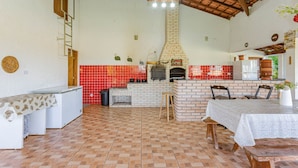 A kitchen with a brick oven, tiled backsplash, and a dining area with a table and chairs.
