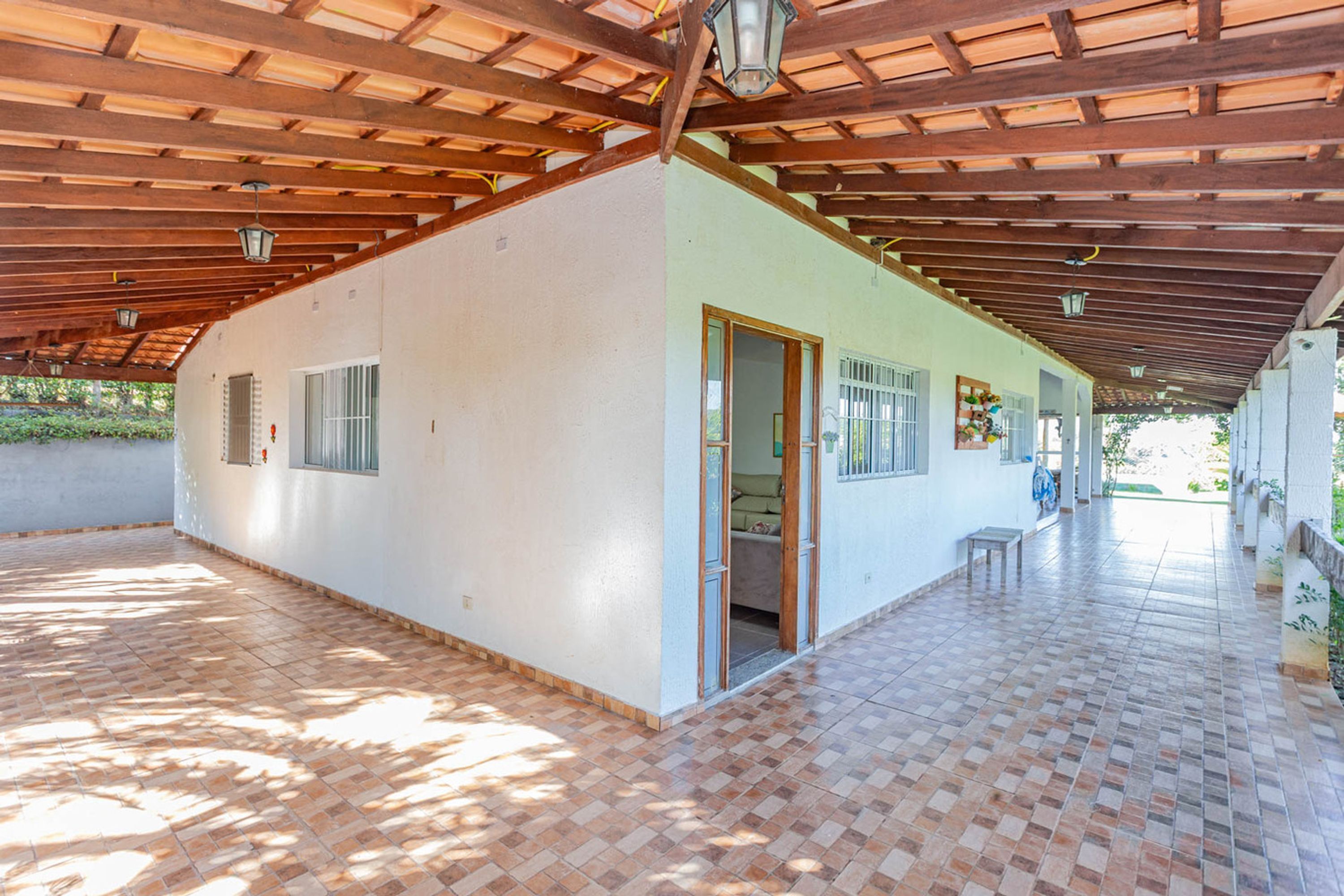 A covered patio area with a tiled floor and a wooden ceiling.