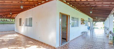 A covered patio area with a tiled floor and a wooden ceiling.