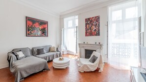 A living room with a sofa set, a round coffee table, a fireplace, and two large paintings. - - (Cannes)