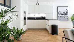 A modern kitchen with white cabinets, a black countertop, and a hanging pendant light.