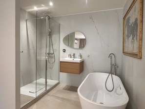 A modern bathroom with a glass-enclosed shower, a freestanding bathtub, and a wooden vanity with a mirror.