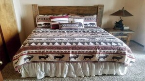 Un lit avec une couvre-lit à motifs représentant des imprimés d’animaux, une tête de lit en bois et une lampe de chevet.