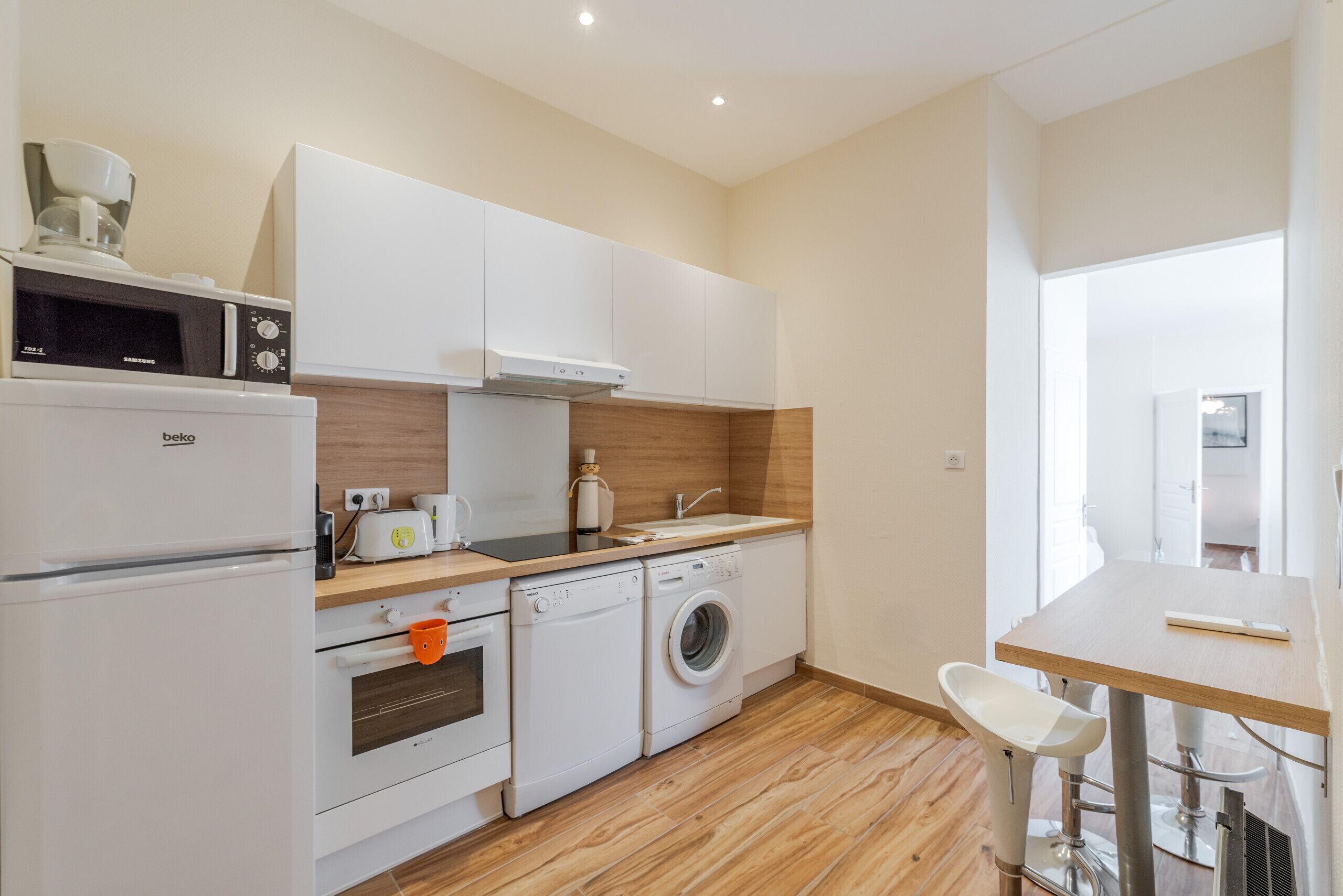 A compact kitchen with a microwave, toaster, oven, and washing machine.