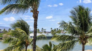 A view of a golf course with palm trees and a body of water in the background.