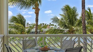 A round table set for dining with a view of palm trees and a body of water.