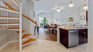 A modern kitchen with a central island, built-in dishwasher, and a dining area with chairs and a table.