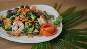 Un plato de verduras salteadas y camarones sobre un plato blanco.