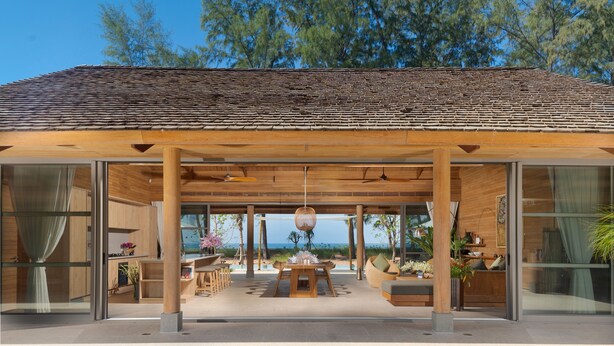 Un espacio lounge moderno al aire libre con una pérgola de madera, una mesa de comedor y arreglos de asientos.