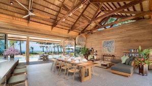 Amplio espacio interior con techo de madera y grandes ventanales con vistas a una piscina.