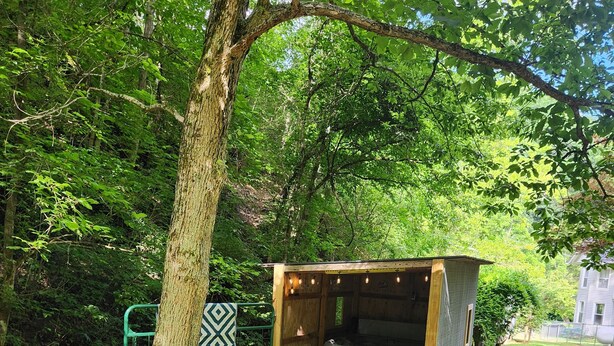 A backyard with a fire pit, a barbecue grill, and a wooden structure.