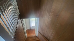 A wooden staircase with a balustrade leading to a room with a window.