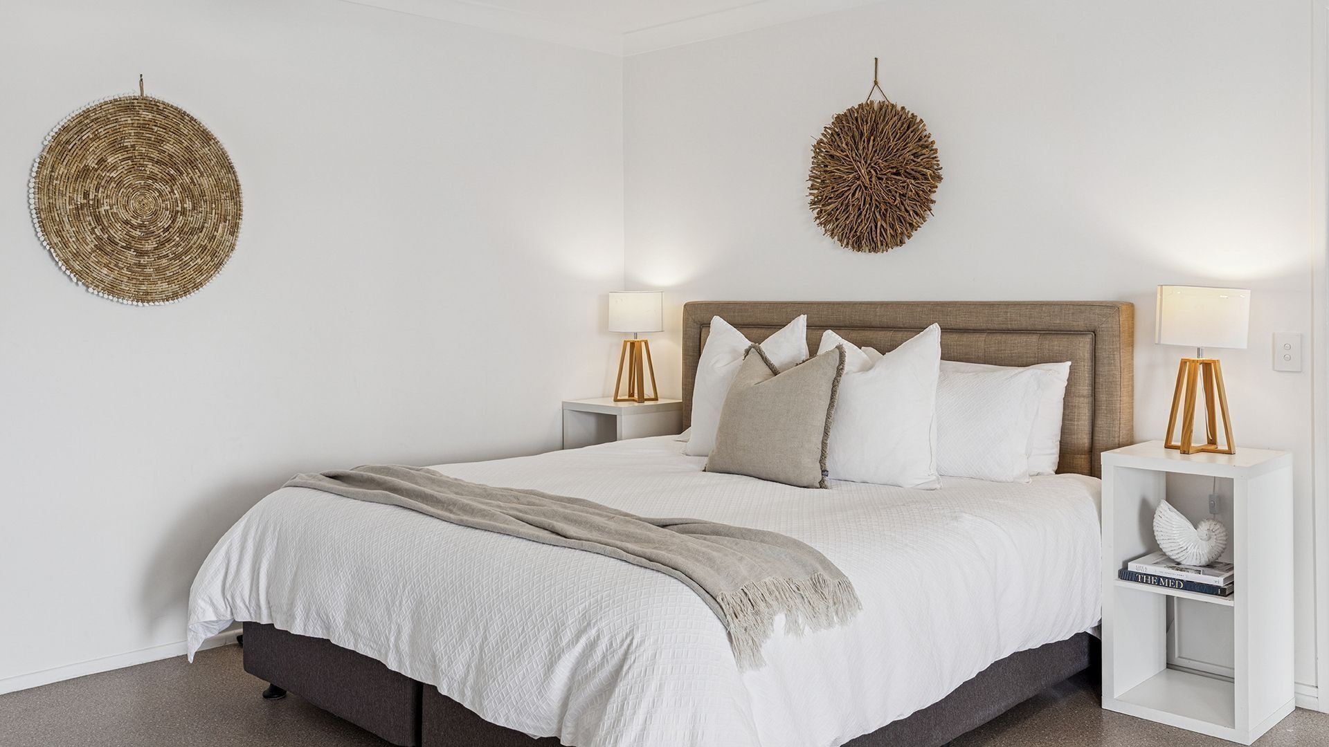 A bedroom with a large bed, two bedside tables, and two wall-mounted lamps.