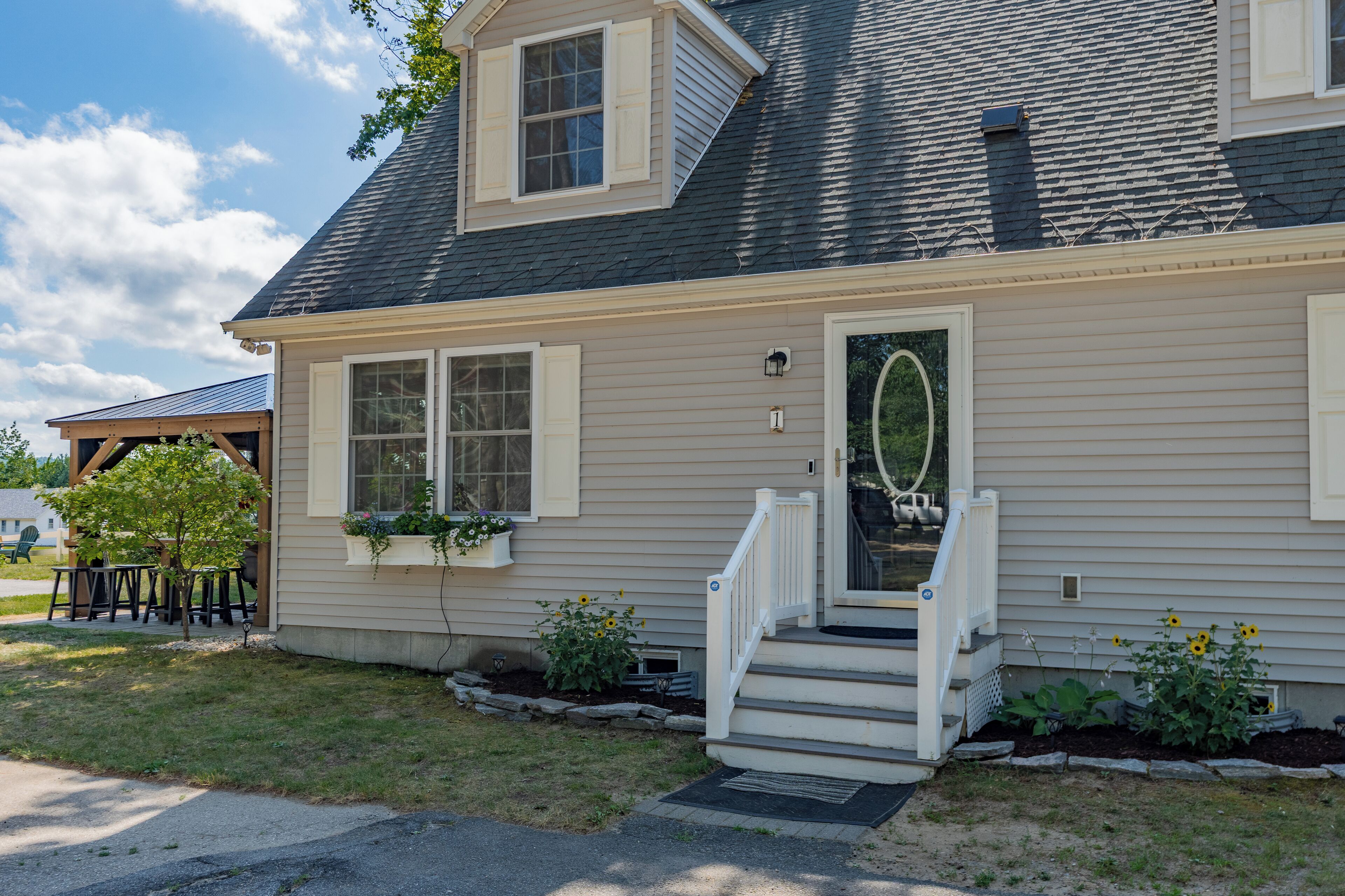 A two-story house with a front porch, a small garden, and a mailbox.