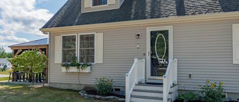 A two-story house with a front porch, a small garden, and a mailbox.