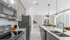 A modern kitchen with stainless steel appliances, a central island, and a view into the dining area.
