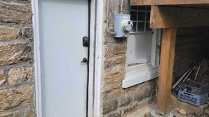 Una pared exterior de piedra, una puerta blanca y una barandilla de balcón de madera.