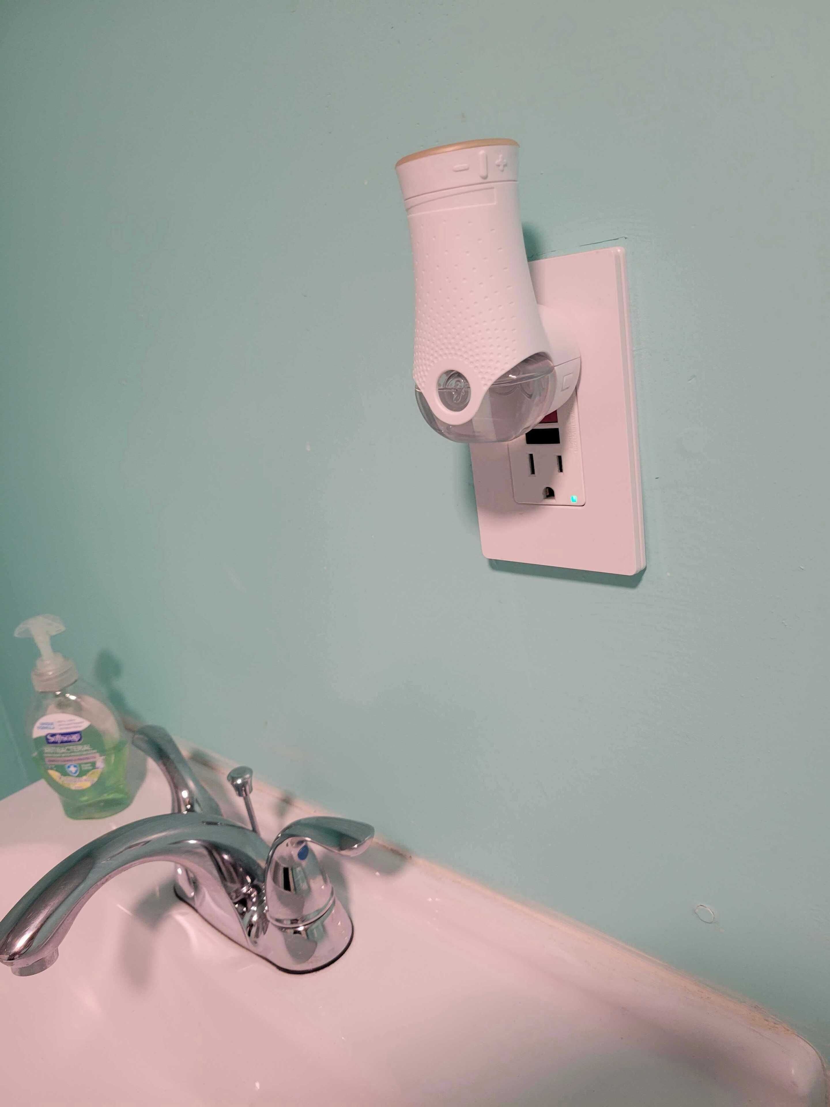 Ett badrum med en vit handfat, en blandare, en tvåldispenser och en pappershandduksdispenser som är monterad på väggen.