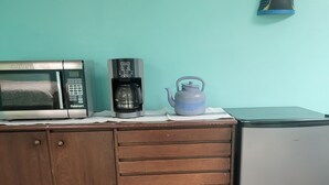 Una kitchenette equipada con microondas, cafetera, hervidor y refrigerador.
