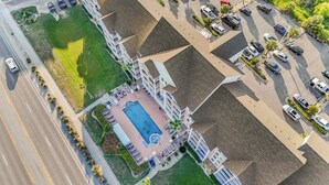 Vista aérea de un hotel con piscina, varios balcones y un estacionamiento.