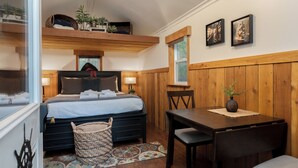 A bedroom with a bed, bedside tables, a small table, and a window.