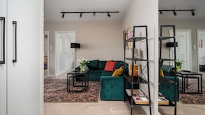 Una sala de estar moderna con un sofá verde, una estantería negra y una alfombra estampada.