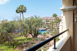 Blick auf ein Hotel mit Schwimmbad, umgeben von Palmen und einem Garten.