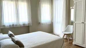 Une chambre à coucher avec un lit, des rideaux blancs, une chaise et une armoire.