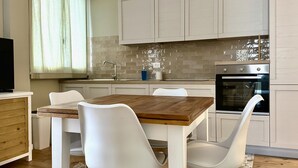 Une cuisine moderne avec des armoires blanches, une table en bois et des chaises blanches.