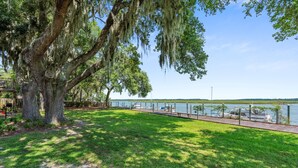 A park with a large tree, a walking path, and a lake with boats.