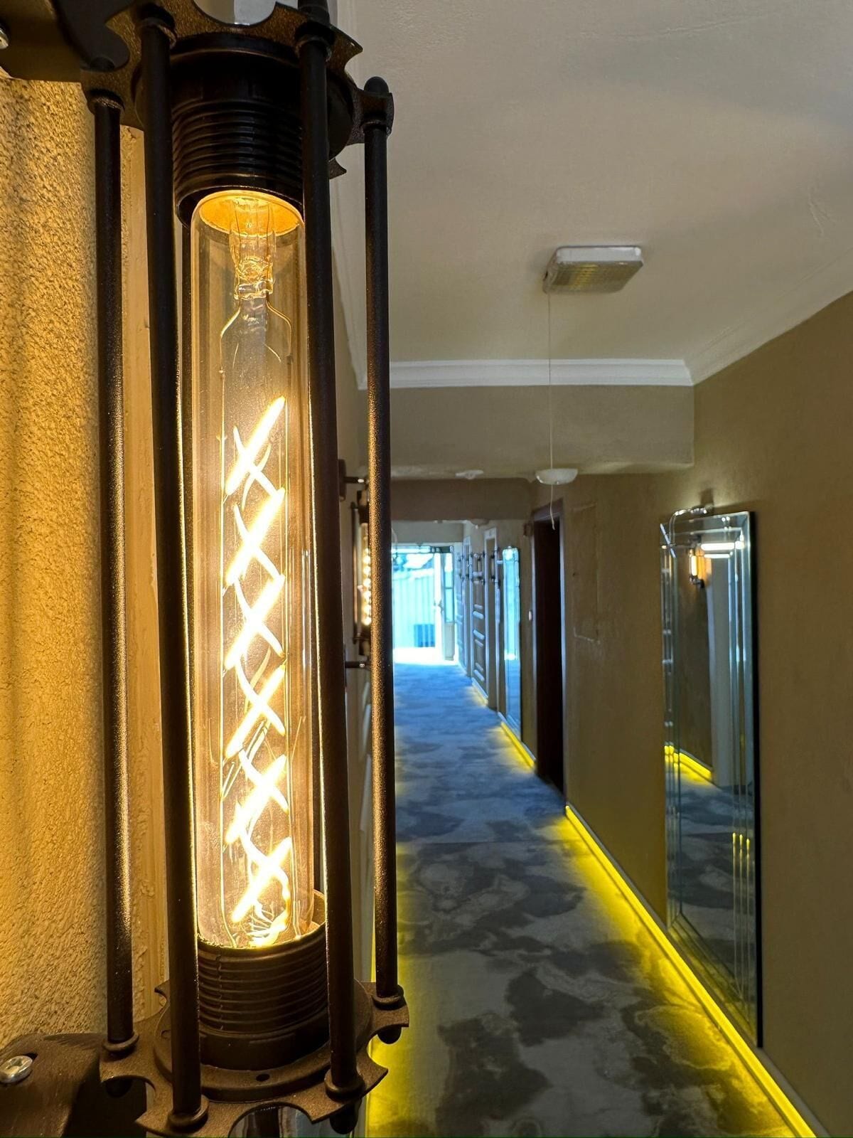 A hallway with a vintage-style light fixture and mirrored walls.