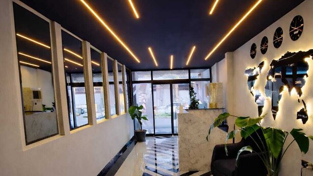 Un vestíbulo moderno con suelo a cuadros blanco y negro, una recepción y una zona de estar con una planta.