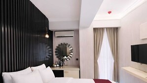 Una habitación de hotel moderna con una cama grande, un escritorio, un televisor y una ventana con cortinas.