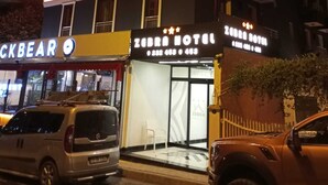 Un hotel con fachada moderna, destacando líneas de neón iluminadas y un letrero llamativo.