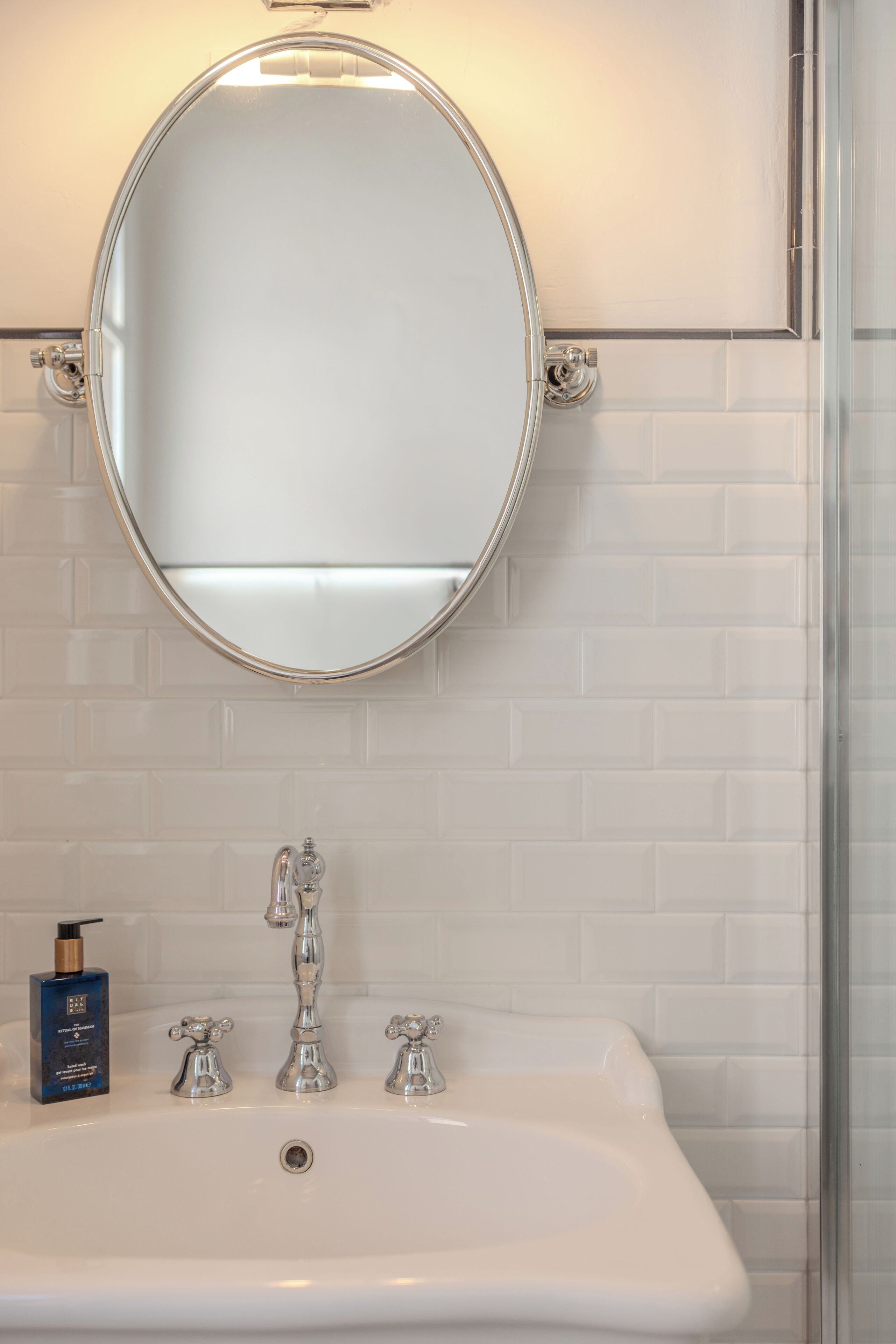 A bathroom with a white sink, two faucets, and a mirror above it.