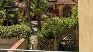 A courtyard with a tiled roof, a wooden fence, and a variety of plants. - B&B Stanze Guelfe (Florence)
